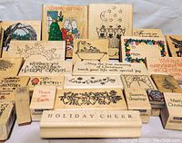 Photo showing the collection of 28 wooden Christmas-themed stamps arranged closely together, displaying various holiday sayings and illustrations.