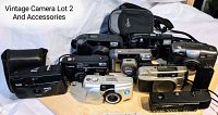 Front overview of all 10 vintage cameras and two camera bags arranged on wooden surface
