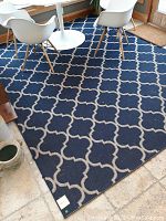 Full view of blue and white area rug with diamond pattern under chairs and table.