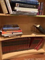 Bookshelf with stacked books including animal themed books and design books, upper shelves shows less organized group of books in various sizes.