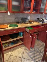 Kitchen countertop and lower open cabinets with food containers, glass jars, wooden cutting boards, and other kitchen accessories.