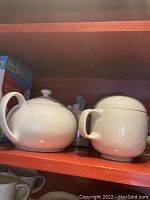 White ceramic teapot and canister on shelf