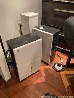 Two Kenmore dehumidifiers side by side on tile floor in basement setting.