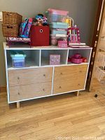 Front and top view showing the dresser with four wooden drawers and three cubbies. Contents on top shown for context and not included.