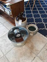 Photo showing a two-toned Number 4 earthenware jug, metal mantel clock on wire stand face-up, flower pot with handles, metal bucket, and a small metal bowl.