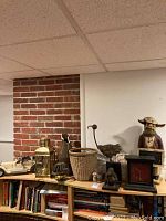 Overview of lot on bookshelf against brick wall showing the figurines, basket, lantern, onyx lamp, and replica car.