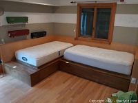 View of L-shaped wood platform and trundle bed with white BeautyRest mattresses and built-in steps.