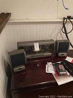 Photo showing the Sharper Image 3-disc CD player with control buttons on top and clear view of cassette compartment, two compact speakers placed on either side.