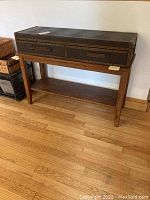 Front view of wooden sofa table showing two attached textured drawers and bottom shelf, wood floor background.