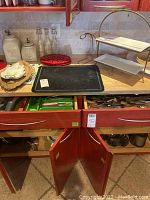 Full view of kitchen counter showing bakeware tray, ceramic canisters, glass bottles, serving stand, decorative plates.