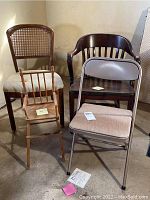 Four chairs arranged: baby doll highchair in front left, caned back chair left rear, solid wood curved back chair right rear, Samsonite folding chair front right.