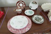 Photo of assorted fine bone china pieces including plates and a tea cup on a wooden surface