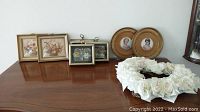 Photo showing the full set of two framed florals, three shadow boxes and the white rose wreath laid out on wooden surface.