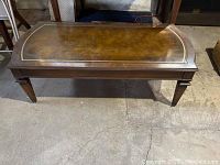 Full view of rectangular mahogany coffee table with leather top showing scratches and wear.