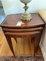 Front view of the three nested Hekman mahogany leather top nesting tables with decorative gold tooling and single drawer with ring pull.