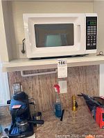 Microwave and espresso machine setup on kitchen counter with other household items.