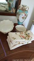 Photo of Nippon vase, Lenox bowls, and folded Lenox linens on wooden surface