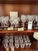 Two shelves displaying sets of various Stuart lead crystal glasses