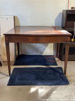 Front view of the vintage Parsons style wood dining table showing top surface wear and tapered legs.