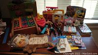 Full display of toys on table including wooden wagon with blocks, plastic red vehicle, action figures, chalk, hand puppet, candle accessories, and other small toys.