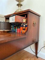 Side angle view of vintage Hekman mahogany leather topped side table showing carved leg and drawer detail with brass handle.