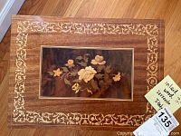 Top view of the wooden music jewelry box showing detailed floral inlay design with cream-colored borders.