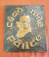 Front view of the copper wall plaque showing hammered and textured background, raised lettering 'Céad Míle Fáilte' around a map of Ireland with central floral motif.