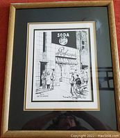 Framed black and white pen and ink etching of Steckman's Ice Cream Parlor storefront with groups of people outside. Bronze wood ribbed frame with double matting.