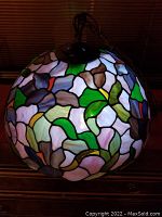 Full view of the dome-shaped Tiffany style stained glass chandelier showing the floral pattern with multi-color glass pieces in green, purple, blue, pink, red, yellow and orange hues, lit to highlight colors.