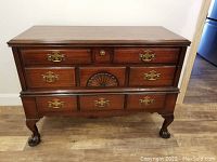 Full front view of the vintage mahogany sideboard showing drawers, claw and ball feet, brass hardware, and carved shell design.