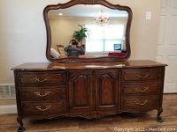 Front view of vintage Drexel Touraine triple dresser with matching large mirror above. Shows dresser drawers, cabinet doors, brass handles, and carved legs.