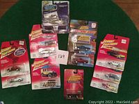 All 11 Johnny Lightning die-cast vehicles shown together on a green background, including tank and cars in original packaging.