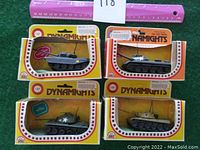 Front view showing four die cast tanks in original Dynamights packaging on green carpet with pink ruler for scale.