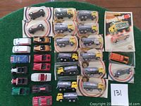 Top view of lot showing vintage toy cars and Mobil tanker trucks in original packaging and loose cars on green felt.