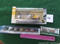 Full view of all 3 packaged die-cast model vehicles on green felt, with pink ruler for scale.