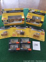 Full lot overview showing nine CAT die cast construction models, five in blister packs, two in larger boxes, and four loose in clamshell boxes.