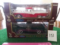Two boxed die-cast Ford model trucks stacked: 1957 Ranchero on top in red and white, 1948 F-1 Pick-Up on bottom in dark color, both in 1:18 scale unopened packaging.