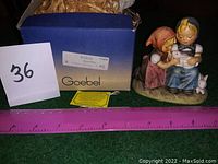 Photo of vintage Goebel Hummel Eastertime figurine with original box, showing two children and rabbits, with a ruler showing size.