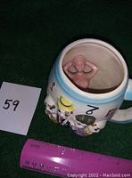 Angle showing top inside of mug with naked lady figure at bottom and exterior quartette design with ruler for scale.