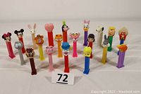 Front view showing entire collection of 20 PEZ dispensers arranged in three rows with various cartoon character heads from Mickey Mouse to Garfield.