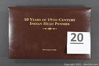 Brown leather-like closed presentation folder measuring approximately 8 by 10 inches with gold embossed lettering reading "10 Years of 19th-Century Indian Head Pennies" by PCS Stamps & Coins.