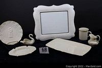 All seven Lenox porcelain items arranged on a black cloth including a tray, picture frame, ashtray, swan, creamer, bridal plate, and mug.