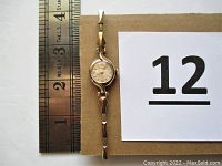 Full top view of watch next to ruler, showing overall design and size