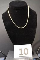 Necklace displayed on black bust form.