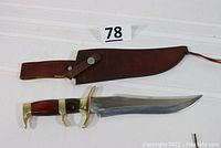 Photo showing knife inside a brown leather sheath with belt loop and Velcro repair on broken loop.