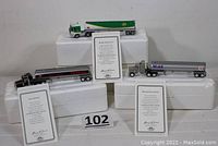 Three collectible tanker trucks displayed on white foam blocks with certificates of authenticity in front of each truck. Trucks include Texaco, Mobil, and BP brands.