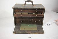 Front view of the wooden toolbox showing the six drawers with oak fronts, open front panel, and key placed in front.