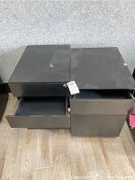 Photo showing two black three-drawer file cabinets side by side, drawers partially opened, one cabinet with keys in lock.