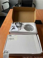 Closed box of Angel POS stand on a table with chairs visible.