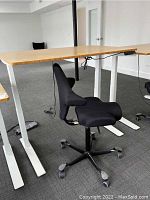 Side view of bamboo desktop on white metal legs with digital controller and adjacent ergonomic chair